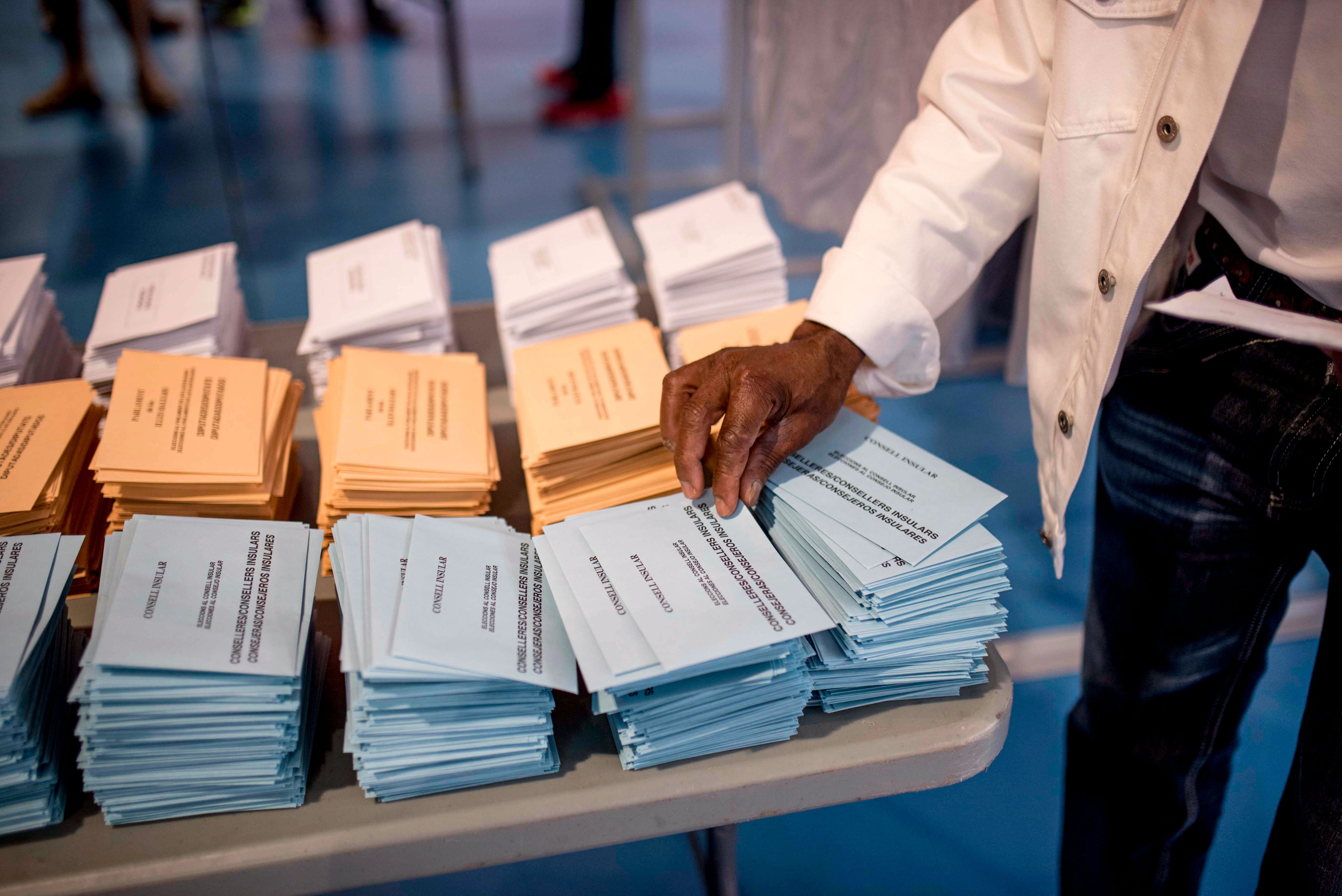 Un hombre escoge una papeleta electoral en el colegio electoral de la Escola Sa Graduada de Mahón (Menorca). 
