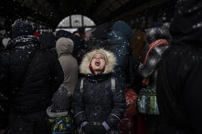 Una niña coge con la boca copos de nieve mientras espera con otros refugiados para subir a un tren con destino a Polonia, en la estación de Lviv en  Ucrania occidental. La ONU ha estimado que el conflicto podría producir hasta 4 millones de refugiados.