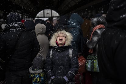 Una niña coge con la boca copos de nieve mientras espera con otros refugiados para subir a un tren con destino a Polonia, en la estación de Lviv en  Ucrania occidental. La ONU ha estimado que el conflicto podría producir hasta 4 millones de refugiados.