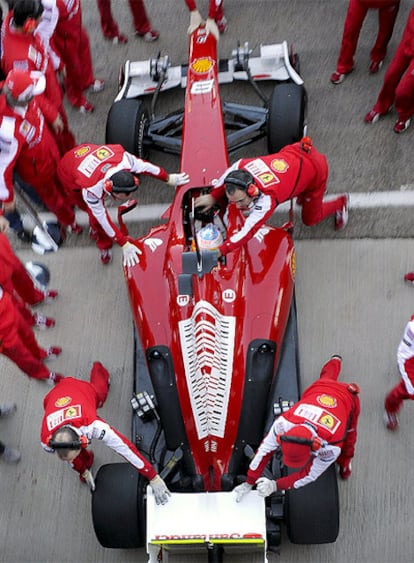 Mecánicos de Ferrari conducen el monoplaza de Fernando Alonso al interior del garaje