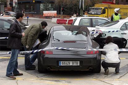 Miembros de la policía científica inspeccionan el automóvil en cuyo interior fue tiroteado ayer un hombre.