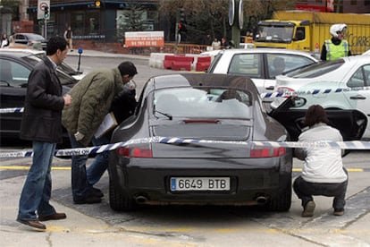 Miembros de la policía científica inspeccionan el automóvil en cuyo interior fue tiroteado ayer un hombre.