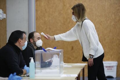 Una treballadora comprova la temperatura dels membres d'una mesa electoral a Ll'Escola Mediterrània, a Barcelona. Perquè les eleccions catalanes transcorrin amb normalitat s'ha convocat a formar part de les meses electorals 82.251 persones, entre titulars i suplents. 31.000 d'elles han presentat al·legacions. 