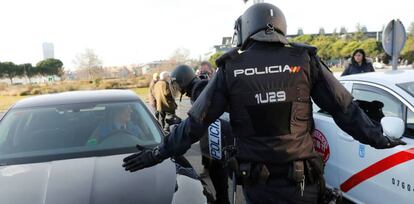 Efectivos de la Polic&iacute;a Nacional entre un veh&iacute;culo de licencia VTC y un taxi a las puertas del recinto ferial de IFEMA.