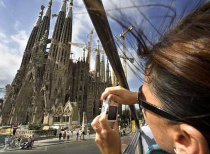 Una turista fotografía la Sagrada Familia desde un autobús en Barcelona.
