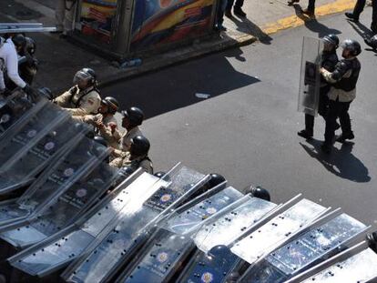 Un manifestante salta sobre los escudos de la polic&iacute;a venezolana.