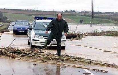 Un agente sortea una carretera inundada ayer en el término municipal de Palomares del Río.