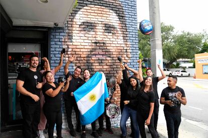 El personal del restaurante Fiorito posa junto a un mural en honor al capitán de la selección argentina, en la ciudad de Miami. 
