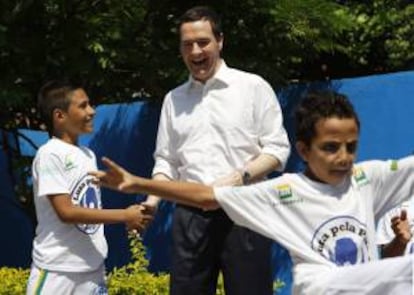 El ministro británico de Economía, George Osborne (c), visita la favela de Maré para conocer el trabajo deportivo realizado por una ONG con la comunidad, este lunes 7 de abril de 2014, en Río de Janeiro (Brasil).