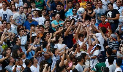 Aficionados en las gradas del Santiago Bernab&eacute;u luchan por un bal&oacute;n lanzado por Theo Hern&aacute;ndez.