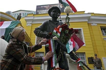 Una mujer decora una estatua de Budapest que representa a los jóvenes que lucharon por la libertad en 1956 en Hungría.