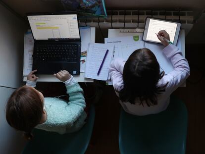 Dos niñas hacen los deberes durante las primeras semanas de confinamiento, en Madrid.