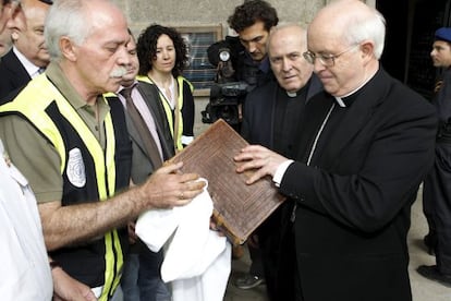 The archbishop of Santiago de Compostela, Juli&aacute;n Barrio, receives the Codex Calixtinus from a police officer on Wednesday. 