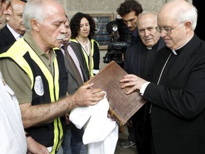 The archbishop of Santiago de Compostela, Juli&aacute;n Barrio, receives the Codex Calixtinus from a police officer on Wednesday. 