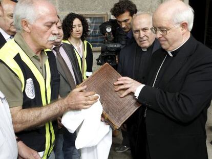 The archbishop of Santiago de Compostela, Juli&aacute;n Barrio, receives the Codex Calixtinus from a police officer on Wednesday. 