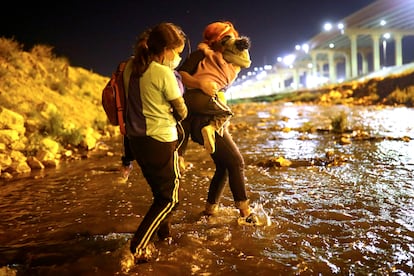 Dos madres con sus hijos en brazos cruzan el Río Bravo en Ciudad Juárez, el 30 de marzo de 2021.