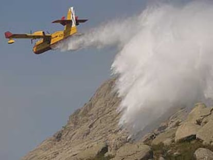 Un hidroavión expulsa agua para sofocar el incendio declarado en el término municipal de Bustarviejo.