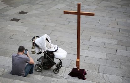 Un hombre consulta su móvil ante una procesión en Santiago de Compostela