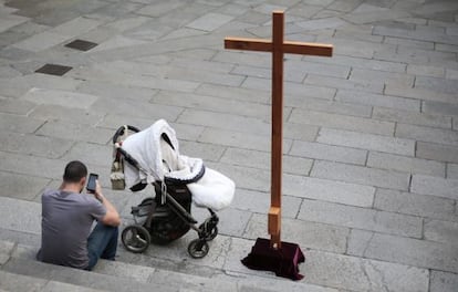 Un hombre consulta su m&oacute;vil ante una procesi&oacute;n en Santiago de Compostela