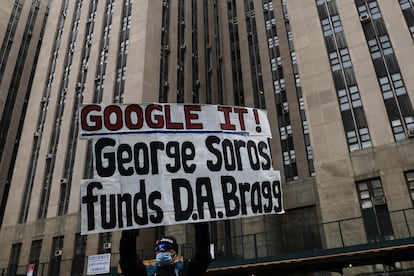 A protestor holds a placard against billionaire investor George Soros outside Manhattan Criminal Court