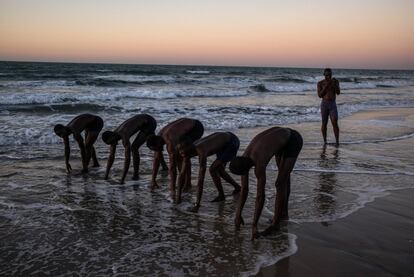 Un grupo de hombres jóvenes se preparan para competir en la playa  de Serekunda (Gambia).