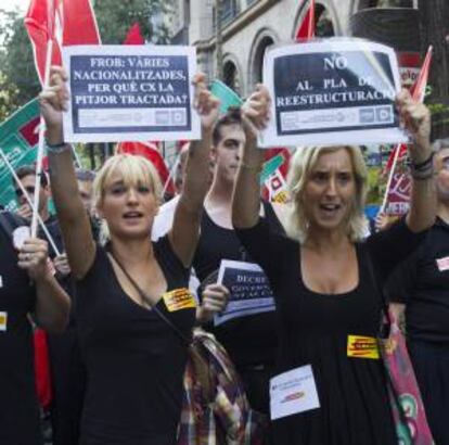 Varias personas portan pancartas durante la manifestación convocada por los representantes sindicales de Catalunya Banc contra el ERE que afecta a la entidad, y que ha congregado hoy en el centro de Barcelona a más de un millar de empleados.