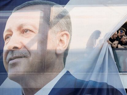 People look out from behind a banner with an image of Turkish President Tayyip Erdogan on a building, during a rally ahead of the May 28 presidential runoff vote, in Istanbul, Turkey May 26, 2023. REUTERS/Murad Sezer