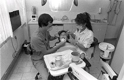 Un médico y una enfermera atienden a un niño en una clínica bucodental. PLANO ENTERO - ESCENA