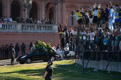 Diego Maradona murió el 25 de noviembre de 2020. El Gobierno argentino organizó con el visto bueno de la familia un velatorio en la Casa Rosada. Decenas de miles de personas desfilaron ante el cajón abierto, pese a las restricciones de la pandemia. En la foto, los fanáticos se cuelgan de las rejas que separan la sede del Ejecutivo de la Plaza de Mayo. Observan la partida del cortejo fúnebre que lleva los restos de Diego Maradona al cementerio de Bella Vista.