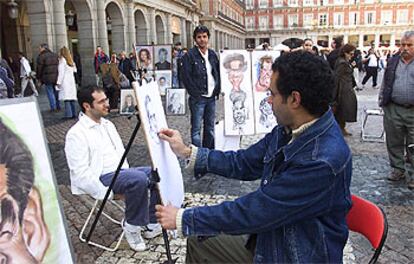 Sadik Shahood dibuja una caricatura en la plaza Mayor. De pie, observándole, su hermano Ghalib.