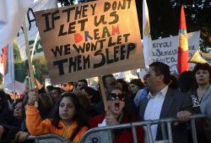 Una manifestante protesta en Chipre y muestra una pancarta en la que se puede leer "si ellos no nos dejan soñar, nosotros no les dejaremos dormir",