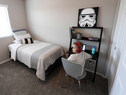 Un niño utiliza el ordenador en su cuarto, en el que hay un cuadro de 'Star Wars'.