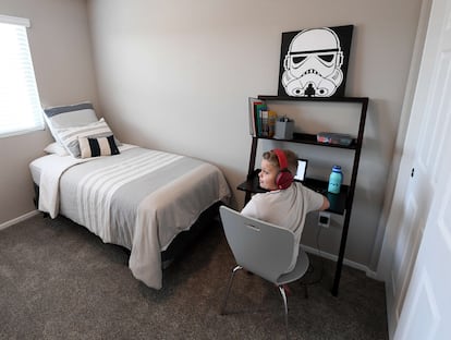 Un niño utiliza el ordenador en su cuarto, en el que hay un cuadro de 'Star Wars'.