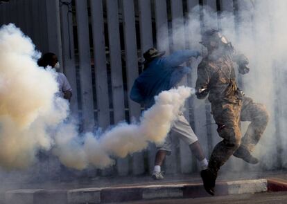 Un par de manifestantes devuelven un bote de gas lacrimógeno a la policía durante los enfrentamientos.