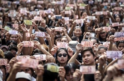 Tailandeses muestran billetes con la imagen del rey Bhumibol Adulyadej a la entrada del hospital Siriraj en Bangkok (Tailandia), donde el monarca falleció a los 88 años de edad.