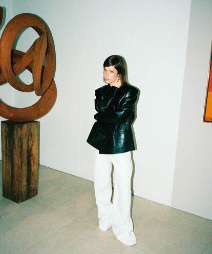 Chaqueta de piel y pantalón de sastre, ambos de MANGO, y pendientes de CHANEL. La escultura de acero 'That’s how I’m feeling', 2024, es de Pieter Obels.