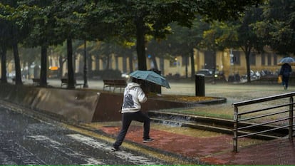 Un peatón cruza una calle entre una fuerte tromba de agua en Pamplona.