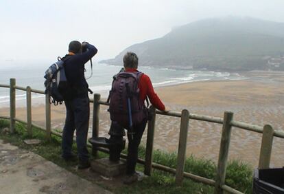 Dos peregrinos contemplan la playa de la Arena, en Zierbena, en el tramo de la costa del Camino de Santiago.