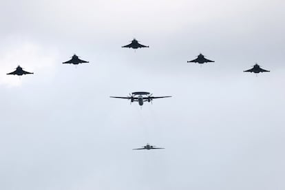 Aviones Rafale escoltan a un E-2 Hawkeye de vigilancia aérea (centro de la imagen) y un Falcón 10 (cerrando la comitiva) durante el desfile aéreo en París.