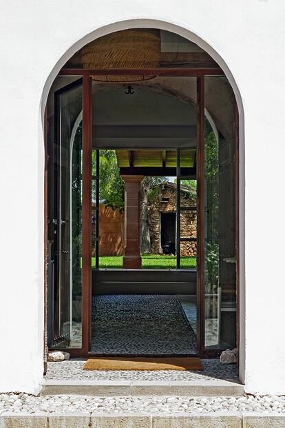 La entrada conecta la casa y sus suelos de hormigón con el jardín, pavimentado con guijarros.