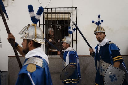 Una mujer mira entre las rejas de su casa a los penitentes vestidos de romanos durante una procesión en Arcos de la Frontera, en Cádiz, el 31 de marzo de 2015.