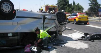 Un guardia civil recoge objetos de la furgoneta volcada.