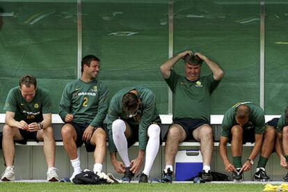 Guus Hiddink, en el centro, sonríe en el banquillo rodeado de cinco futbolistas australianos.