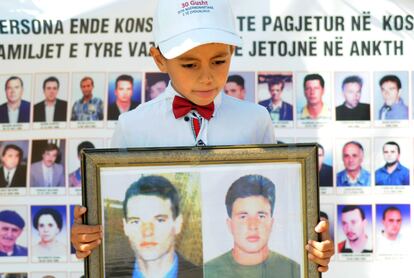 Un niño con las imágenes de dos desaparecidos durante la conmemoración del Día Internacional de los Desaparecidos, en agosto de 2019 en Pristina.