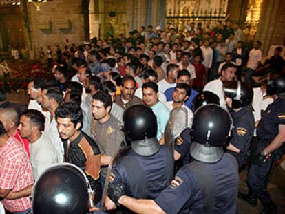 Agentes antidisturbios, junto al altar de la catedral de Barcelona, dirigen a los inmigrantes hacia la salida del templo.