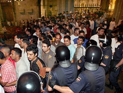 Agentes antidisturbios, junto al altar de la catedral de Barcelona, dirigen a los inmigrantes hacia la salida del templo.