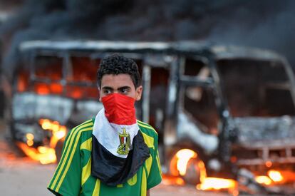 Un joven permanece frente a un autobús de los Hermanos Musulmanes envuelto en llamas, tras los enfrentamientos contra opositores a esta formación en las inmediaciones de la sede principal del grupo islamista, en el barrio cairota de Al Moqatam en El Cairo (Egipto).