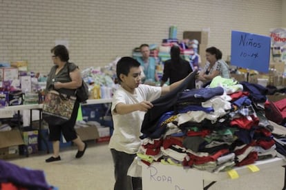 Un niño busca ropa en un albergue de Texas