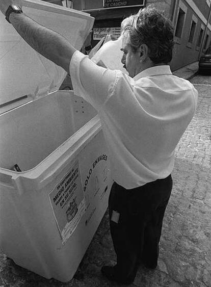 Un hombre deposita basura en un contenedor de envases.