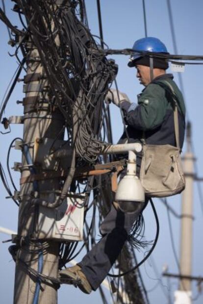 Ingenieros trabajan en postes de electricidad de Pekín (China).